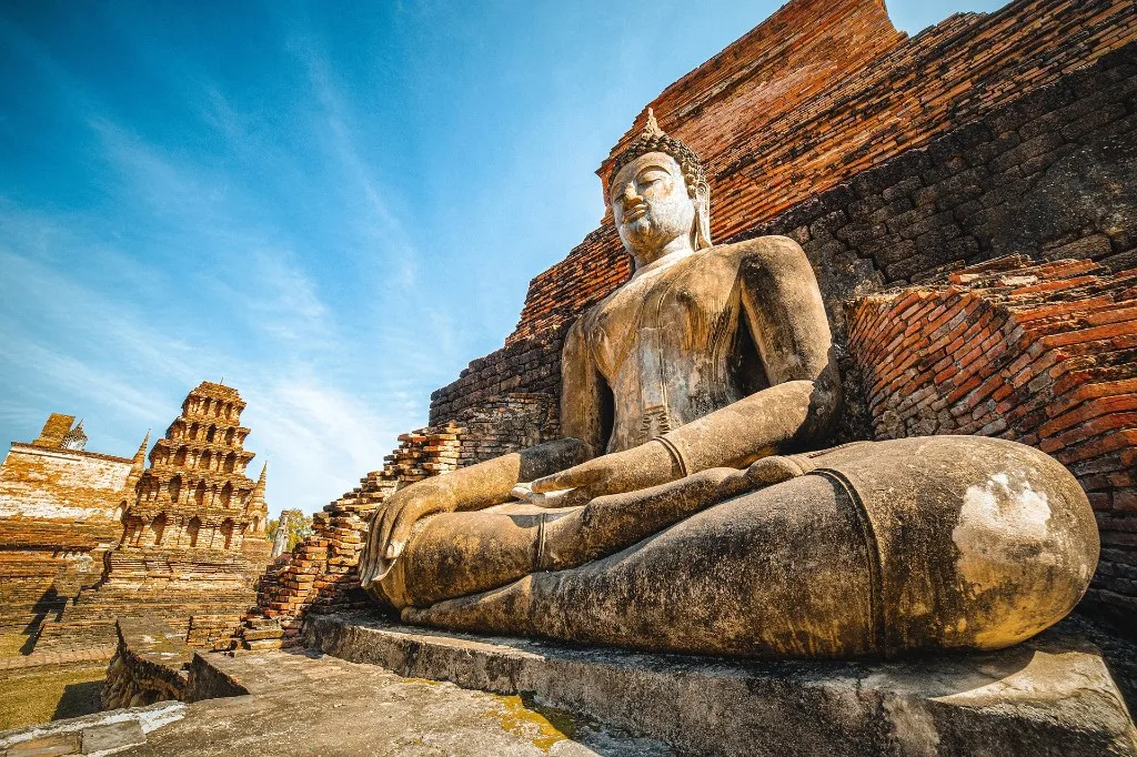 Tomorrowland Thailand 2026: seated Buddha statue before the brick ruins of Ayutthaya